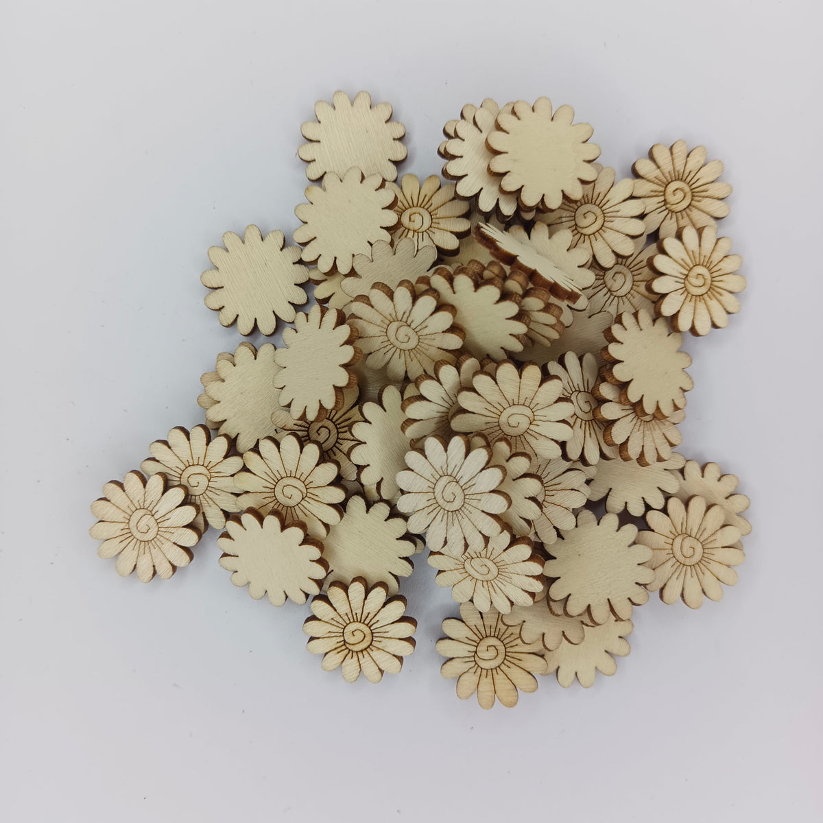 20mm Wood Sunflower Embellishments – A pile of small natural wood daisy-shaped craft embellishments on a plain light gray background.