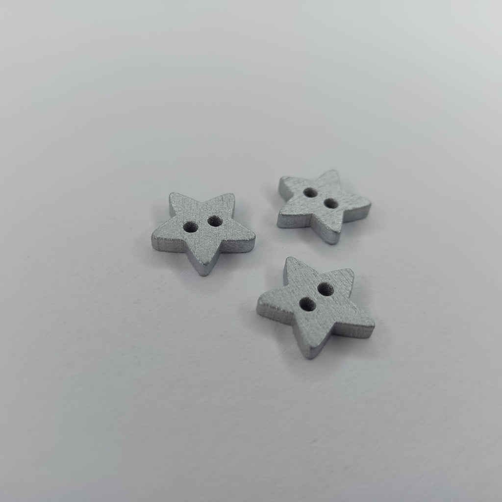 Star Wood Buttons 13mm 2 Holes – Silver & Gold – Three small star-shaped buttons with two holes, finished in a textured light gray, arranged on a plain light gray background.